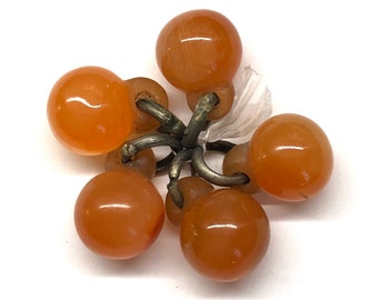 May include: A cluster of six orange glass beads connected by silver metal rings. The beads are round and smooth.