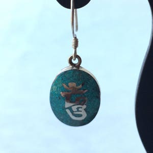 May include: Silver dangle earrings with a turquoise oval charm featuring a silver Chinese character.