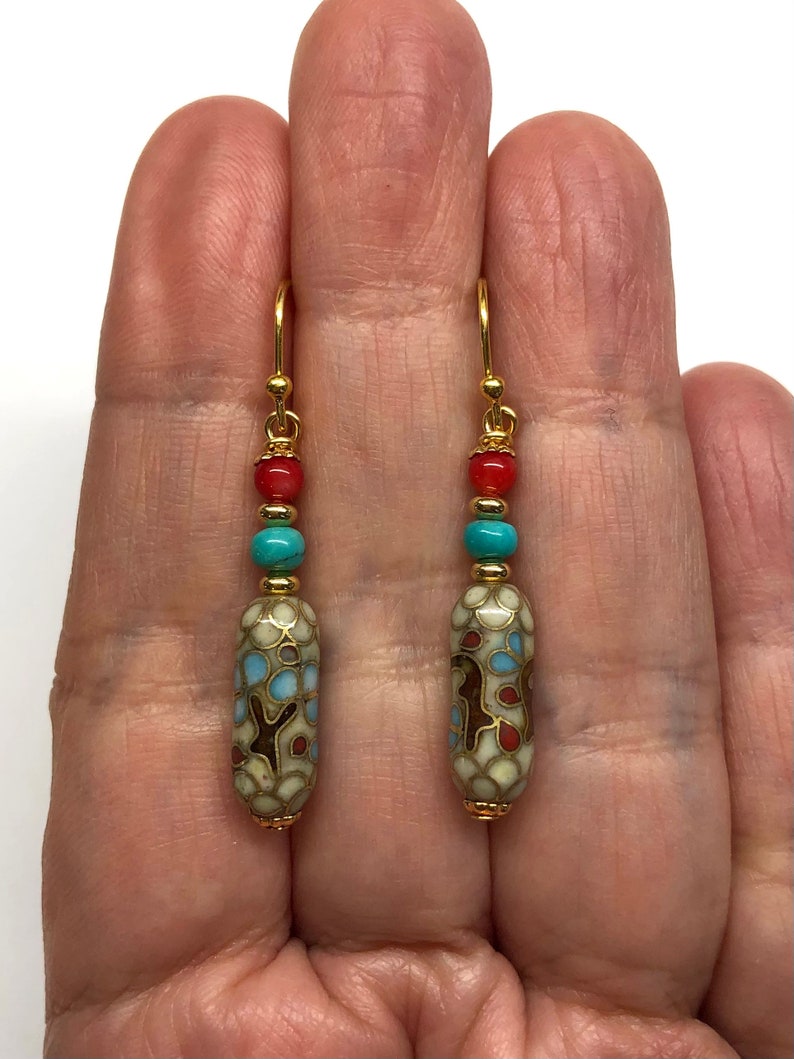 May include: Gold dangle earrings with a white, blue, and red patterned bead, turquoise bead, and coral bead.