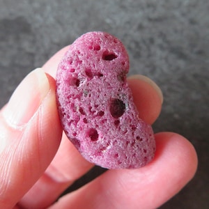 Può includere: Una roccia rosa a forma di cuore, porosa e con una texture ruvida.