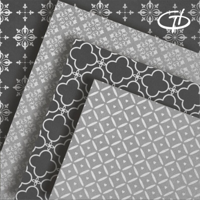 May include: An assortment of patterned paper sheets in shades of gray and white. The designs include floral, quatrefoil, and geometric patterns. The paper sheets are arranged in a layered, angled composition, showcasing the variety of designs.