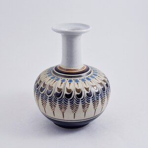 May include: A white ceramic vase with a round body and a narrow neck. The vase is decorated with a blue, brown, and gold geometric pattern.