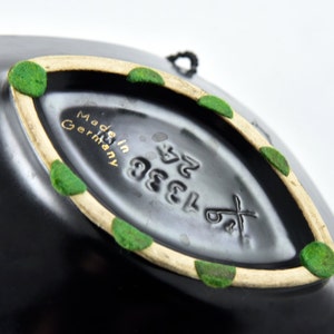 May include: Black ceramic bowl with a white rim and green accents. The bottom of the bowl has the text "Made in Germany" and the number "1383 52".