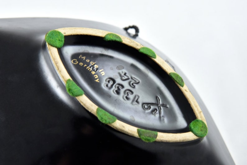 May include: Black ceramic bowl with a white rim and green accents. The bottom of the bowl has the text "Made in Germany" and the number "1383 52".