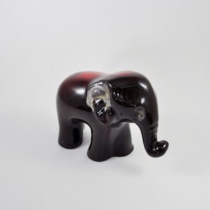 May include: A black and red ceramic elephant figurine with a glossy finish. The elephant has a raised trunk and its ears are slightly flared.