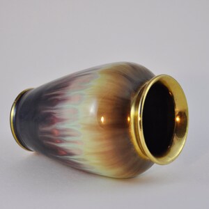 May include: A ceramic vase with a gold rim and a colourful, iridescent glaze. The glaze features shades of purple, brown, and green.
