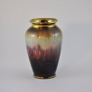 May include: A brown and gold ceramic vase with a mottled glaze. The vase has a rounded body and a narrow neck.