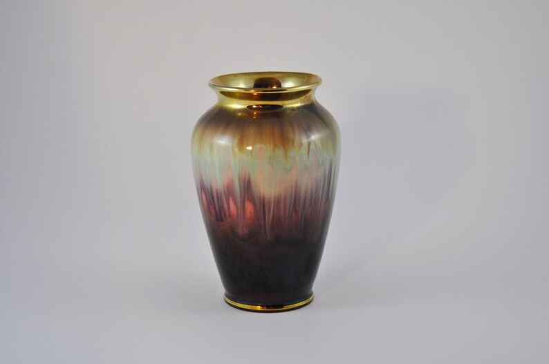 May include: A brown and gold ceramic vase with a mottled glaze. The vase has a rounded body and a narrow neck.
