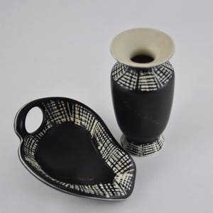 May include: A black and white ceramic vase and a black and white ceramic dish with a handle. Both pieces have a geometric pattern.