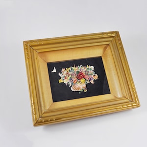 Peut inclure: Nature morte florale encadrée. L'œuvre présente un bouquet de fleurs dans un vase en forme de coquillage sur fond noir. Le cadre est de couleur or clair avec un bord décoratif.
