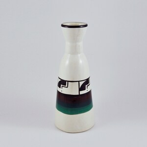 May include: White ceramic vase with a black and green geometric design. The vase has a narrow neck and a wide base.