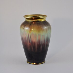 May include: A ceramic vase with a gold rim and a gradient of colours from dark purple to light green.