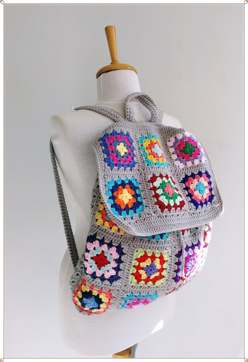 Pu&ograve; includere: Uno zaino in crochet grigio con quadrati di granny colorati. Lo zaino ha una chiusura a coulisse e spalline regolabili.