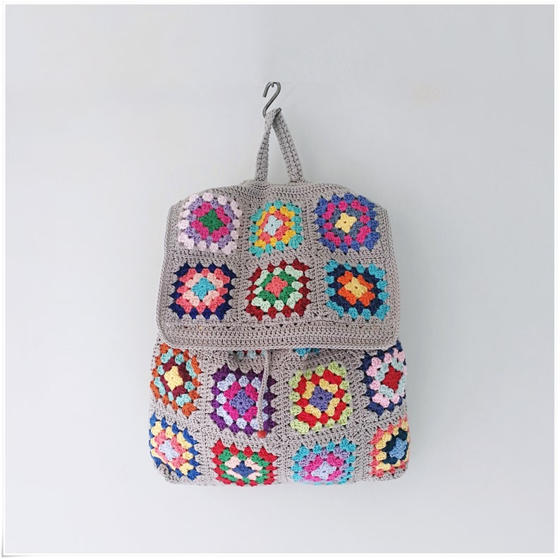 Pu&ograve; includere: Uno zaino in crochet grigio con toppe quadrate a nonna colorate. Lo zaino ha una chiusura a coulisse e spalline regolabili.