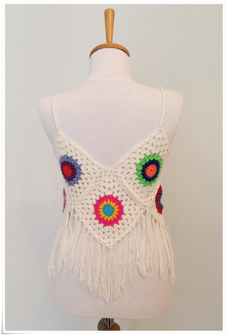 Puede incluir: Top blanco de crochet con detalles florales coloridos y ribete de flecos.