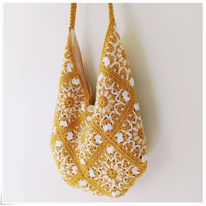 Puede incluir: Una bolsa de mano de crochet amarilla con dise&ntilde;os florales blancos. La bolsa tiene un cierre de bot&oacute;n &uacute;nico.