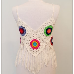 Puede incluir: Top blanco de crochet con dise&ntilde;os florales coloridos y ribete de flecos.