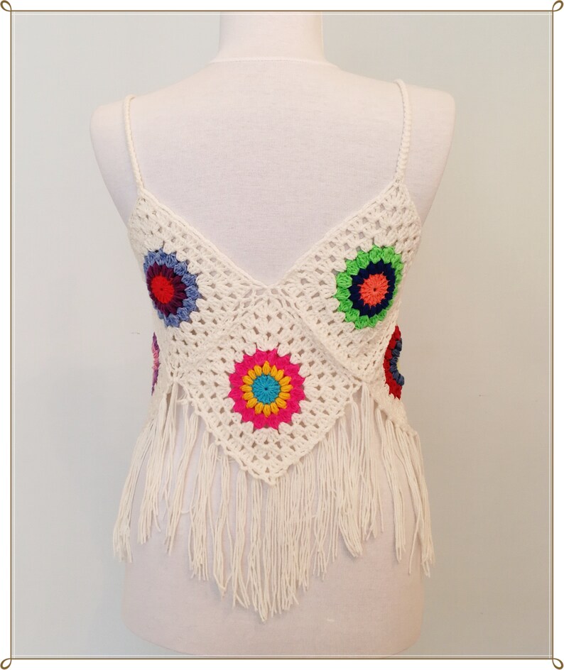 Puede incluir: Top blanco de crochet con dise&ntilde;os florales coloridos y ribete de flecos.