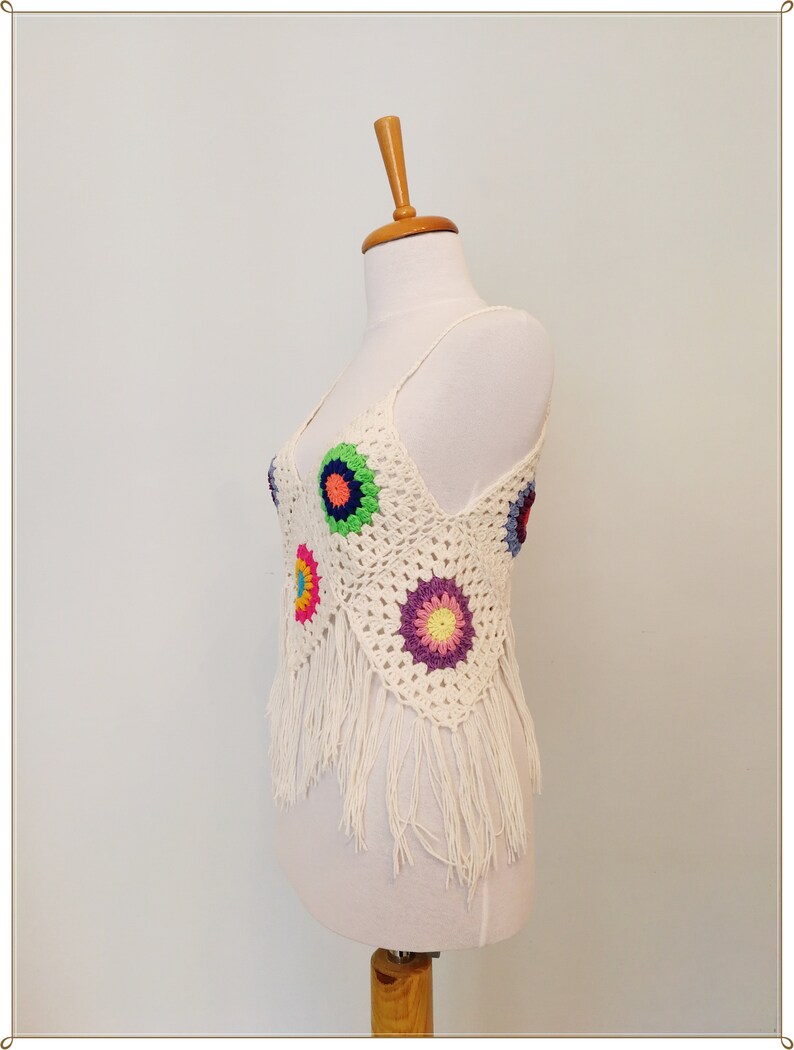 Puede incluir: Top blanco de crochet con dise&ntilde;os florales coloridos y ribete de flecos.
