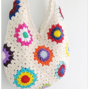 May include: A white crocheted tote bag with colorful granny squares. The bag has a single button closure and a long strap.