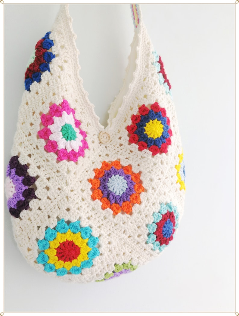 May include: A white crocheted tote bag with colorful granny squares. The bag has a single button closure and a long strap.