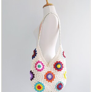 May include: A white crochet tote bag with colorful granny squares. The bag has a long strap and is perfect for carrying everyday essentials.
