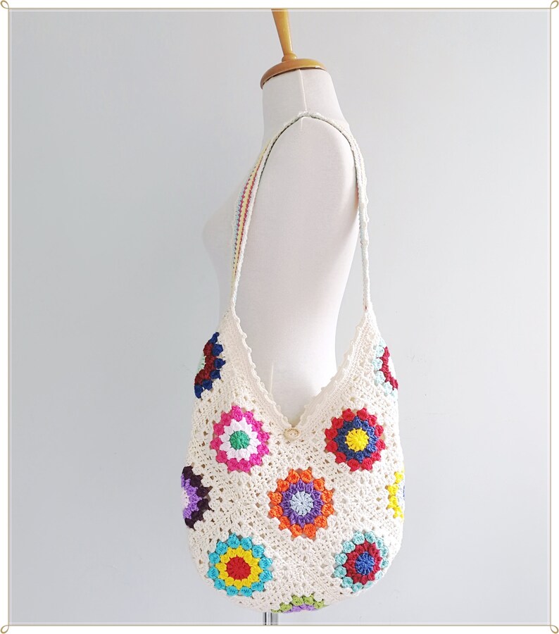 May include: A white crochet tote bag with colorful granny squares. The bag has a long strap and is perfect for carrying everyday essentials.