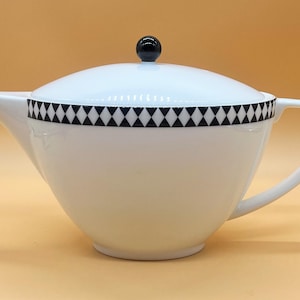 May include: White teapot with a black and white diamond pattern around the rim and a black knob on the lid.