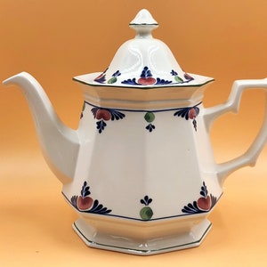 Pode incluir: Bule de chá de cerâmica branca com um design floral azul e verde. A chaleira tem uma tampa e uma alça.