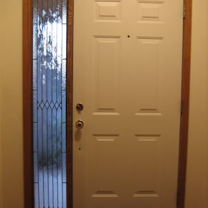 May include: A white door with a single pane glass window with a wood frame. The door has six panels and a brass door knob.