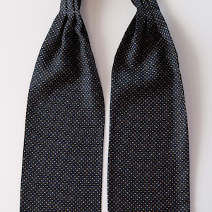 Puede incluir: Una corbata azul oscuro con un pequeño patrón de lunares blancos y naranjas.