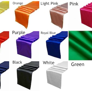 Peut inclure: Un ensemble de 12 chemins de table en satin de diff&eacute;rentes couleurs, notamment jaune, orange, rose clair, rose, rouge, violet, bleu royal, vert, bleu marine, noir, blanc et vert. Les chemins de table sont tous pli&eacute;s en trois et dispos&eacute;s sur un fond blanc.