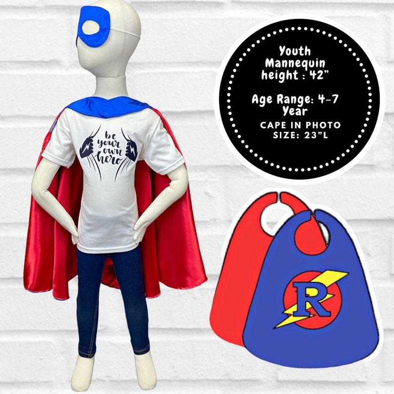 May include: A mannequin dressed in a superhero costume, including a white t-shirt with the text "be your own hero", a red cape, blue jeans, and a blue eye mask. The cape is 23 inches long. The mannequin is 42 inches tall and is for ages 4-7.
