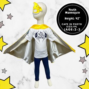 K&ouml;nnte beinhalten: Ein gelber und silberner Umhang mit einem wei&szlig;en T-Shirt, auf dem "be your own hero" steht. Die Schaufensterpuppe tr&auml;gt eine blaue Jeans und eine gelbe Maske. Jugend-Schaufensterpuppe H&ouml;he: 42" CAPE IN PHOTO SIZE:19L (AGE:2-3