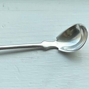May include: A silver teaspoon with a rounded bowl and a long, slender handle. The handle is engraved with the initials "O.H."