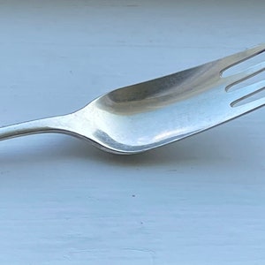 May include: A silver fork with an ornate handle and a simple, three-pronged head.