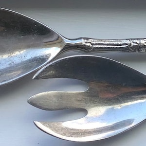 Könnte beinhalten: Ein Set aus zwei silbernen Salatbesteck mit Bambus-Griffen. Das Besteck besteht aus einem Löffel und einer Gabel.