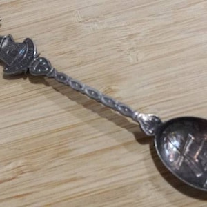 Pode incluir: Colher de prata com um design de moinho de vento no cabo e uma imagem de moinho de vento na tigela.