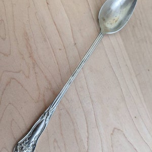 Peut inclure: Une cuillère en argent, ornée, à long manche avec un motif floral sur le manche.