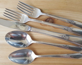 May include: A set of five silver-plated flatware pieces, including a knife, two forks, and two spoons. The pieces have ornate floral designs.