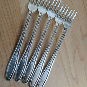 Puede incluir: Conjunto de cinco tenedores plateados con diseños ornamentados. Los tenedores tienen un estilo clásico y vintage.