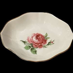 May include: A white porcelain bowl with a gold rim and a pink rose design.