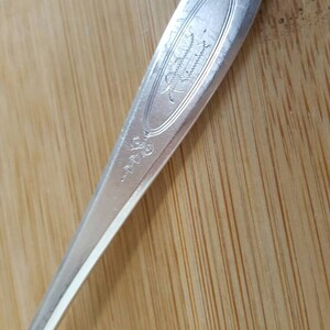 May include: Close-up of the handle of a silver spoon with an ornate design and the inscription "International Silver Co."