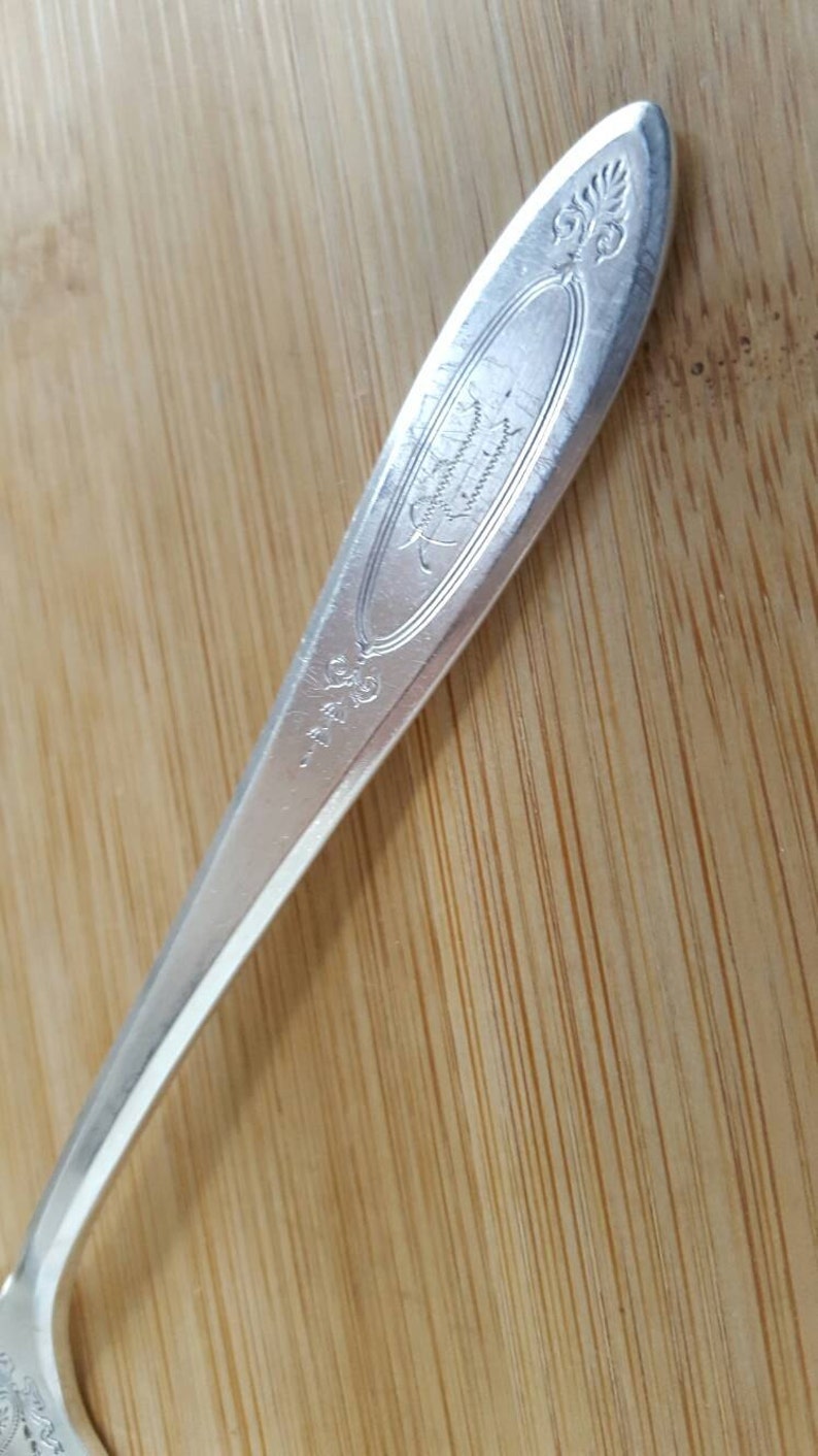 May include: Close-up of the handle of a silver spoon with an ornate design and the inscription "International Silver Co."