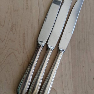 May include: Three silver dinner knives with ornate handles.