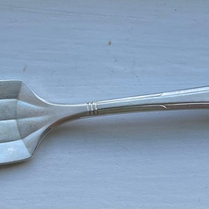 May include: A silver fork with four tines and a slightly curved handle.
