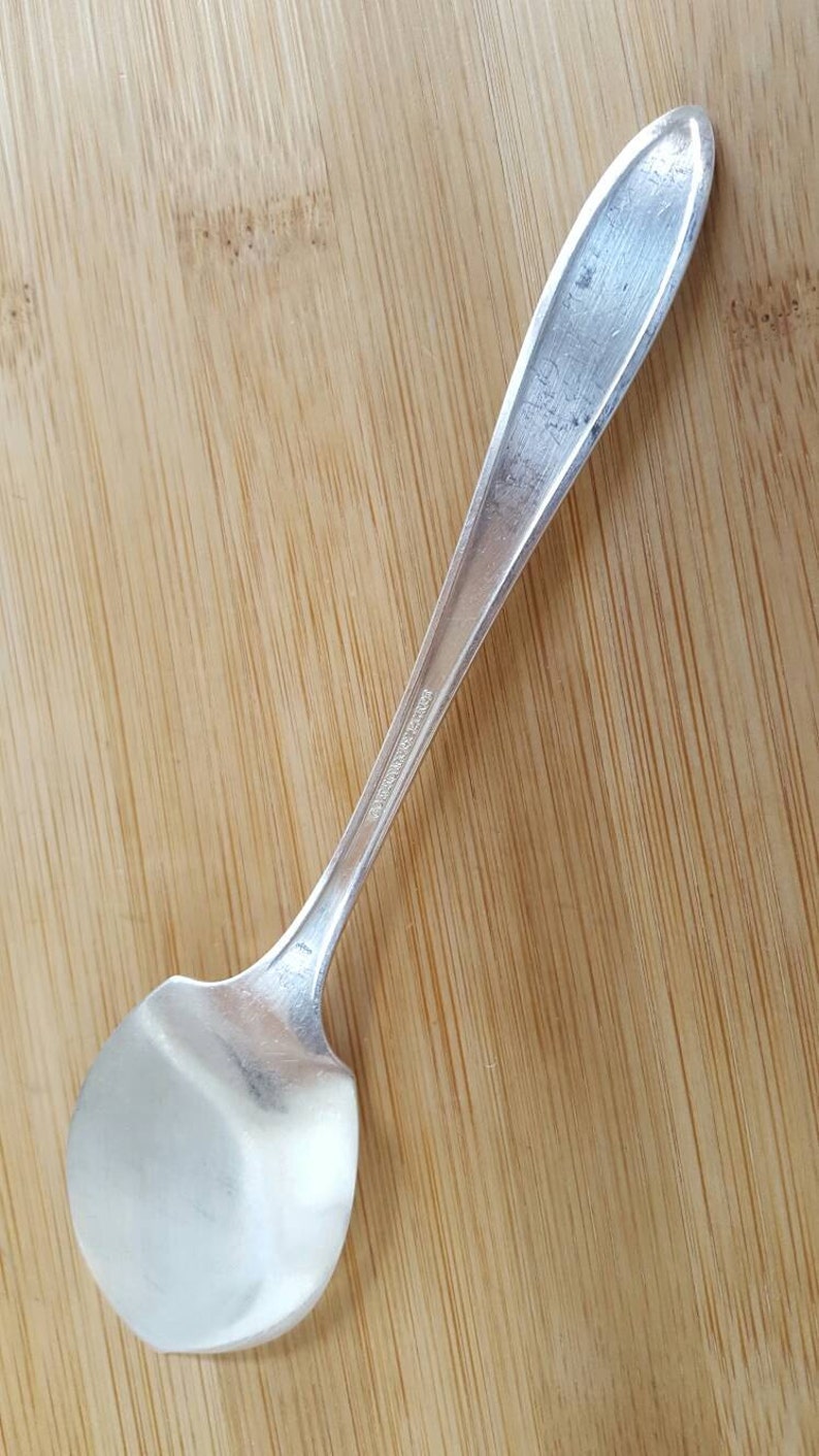 May include: A silver spoon with a rounded bowl and a long, slender handle. The handle has the inscription "International Silver Co." on it.