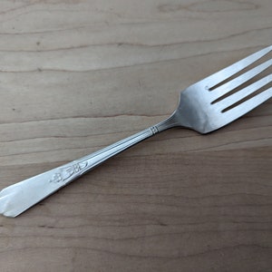 Könnte beinhalten: Eine silberne Gabel mit einem dekorativen Design am Griff.