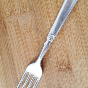 Peut inclure: Une fourchette en argent avec un manche orné sur une surface en bois.