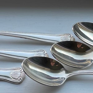 Peut inclure: Ensemble de six cuillères à café en argent avec des manches ornés. Les cuillères sont polies et brillantes, reflétant la lumière.